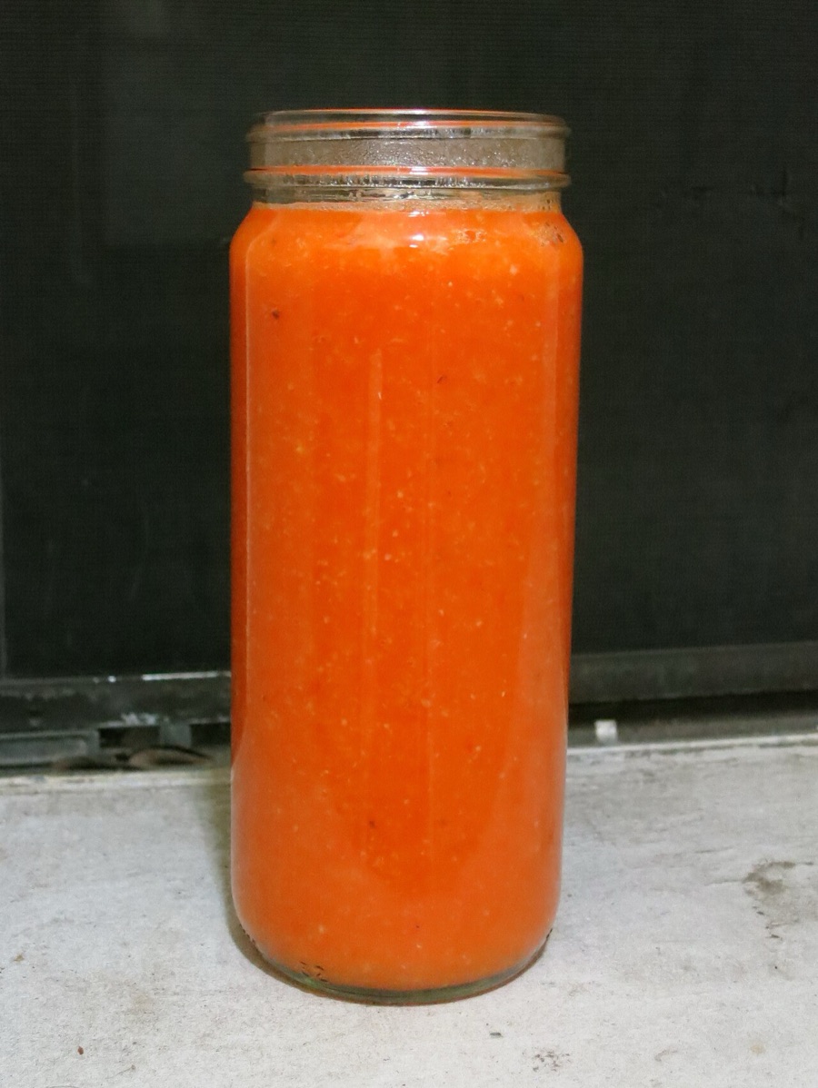 A glass jar of fiery homemade pepper sauce